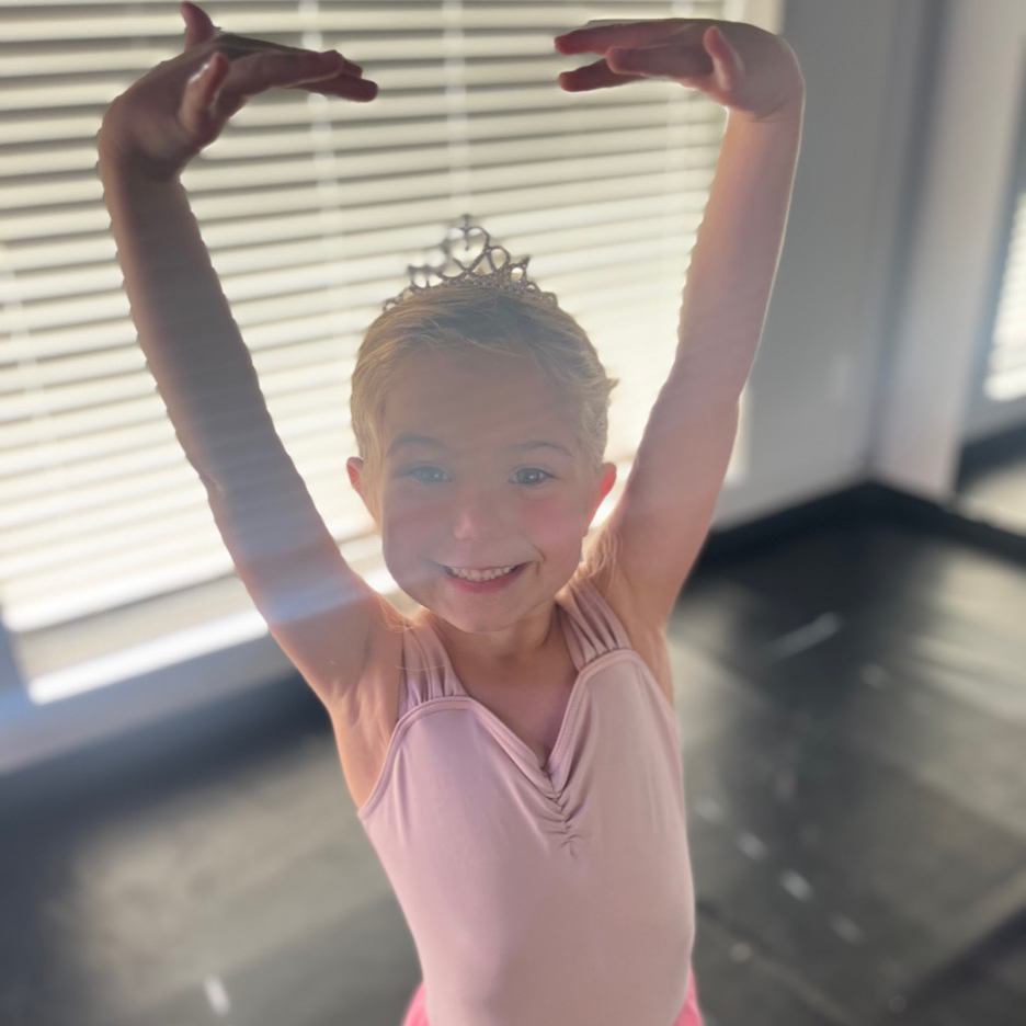 Young child learning stretches and ballet basics.