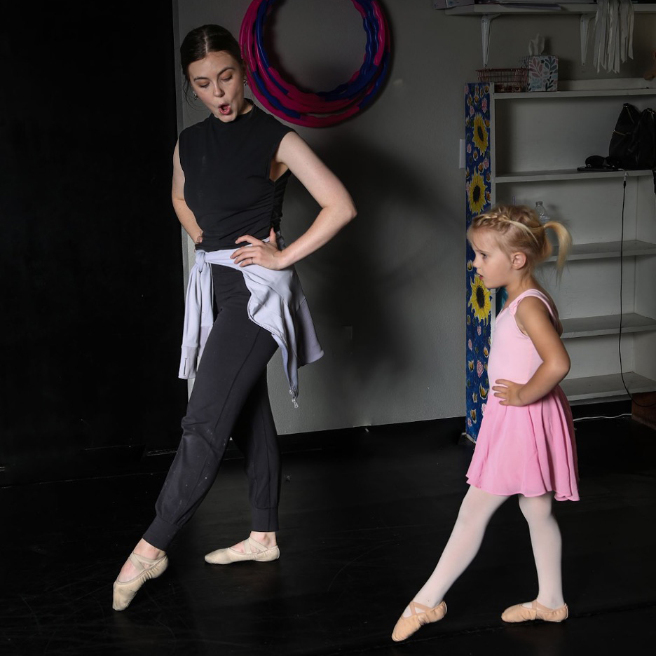 Teacher demonstrates dance position to student.